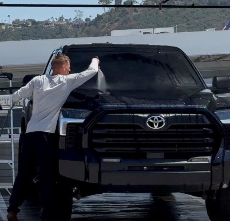 Detailer hand washing a black Toyota Tundra on location